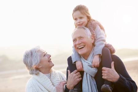 Grandparents And Granddaughter Walking On Winter Beach